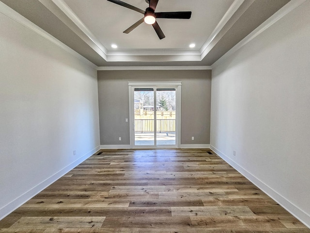 spare room featuring ceiling fan, crown molding, wood-type flooring, and a tray ceiling