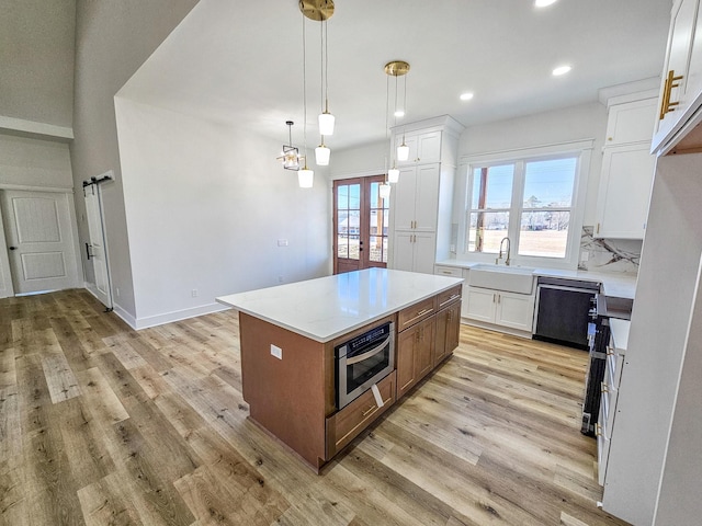 kitchen with white cabinets, a center island, sink, hanging light fixtures, and oven