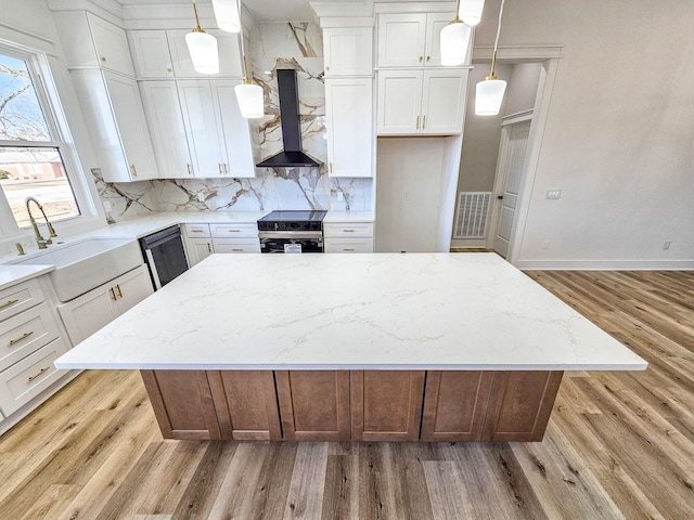 kitchen featuring white cabinetry, hanging light fixtures, and wall chimney range hood