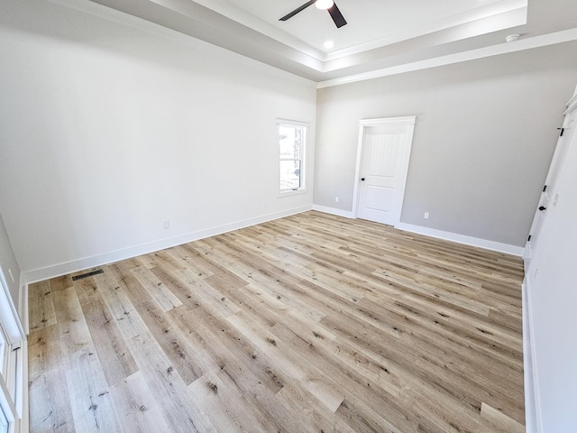 spare room with ceiling fan, a tray ceiling, and light hardwood / wood-style flooring