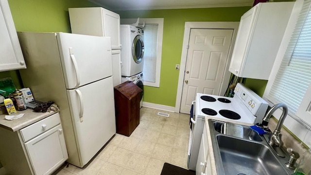 kitchen featuring sink, crown molding, white appliances, stacked washer and dryer, and white cabinets