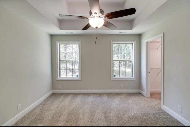 carpeted spare room featuring a raised ceiling and ceiling fan