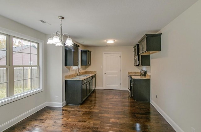 kitchen with pendant lighting, appliances with stainless steel finishes, sink, dark hardwood / wood-style floors, and a chandelier