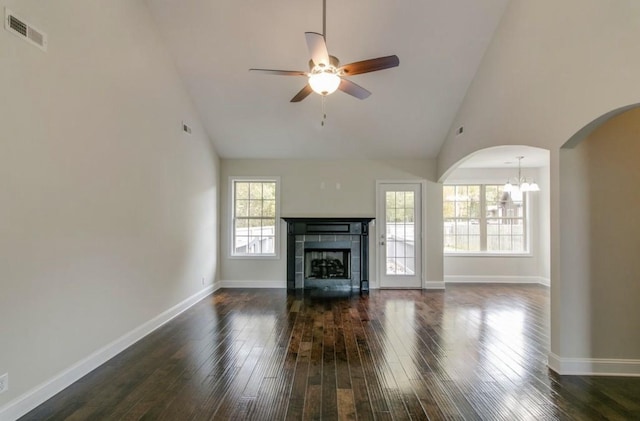 unfurnished living room with high vaulted ceiling, a tiled fireplace, dark wood-type flooring, and a wealth of natural light