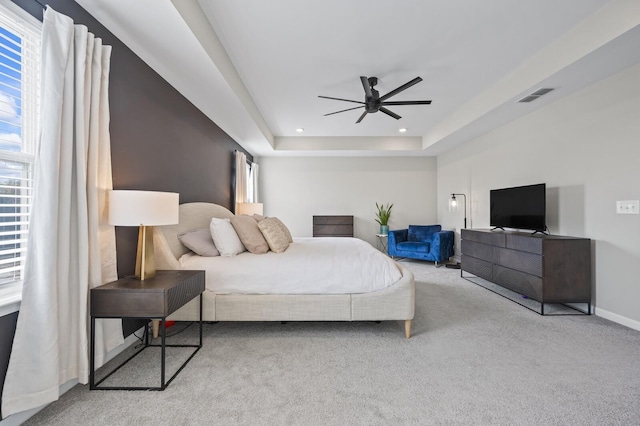 carpeted bedroom featuring ceiling fan and a tray ceiling