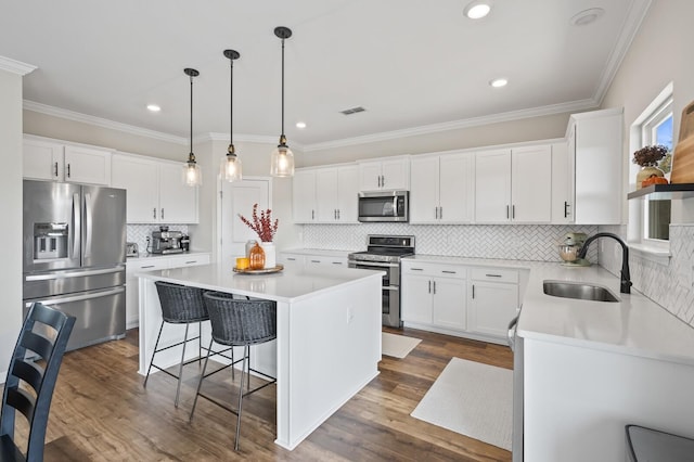 kitchen featuring white cabinets, hanging light fixtures, appliances with stainless steel finishes, and a kitchen island