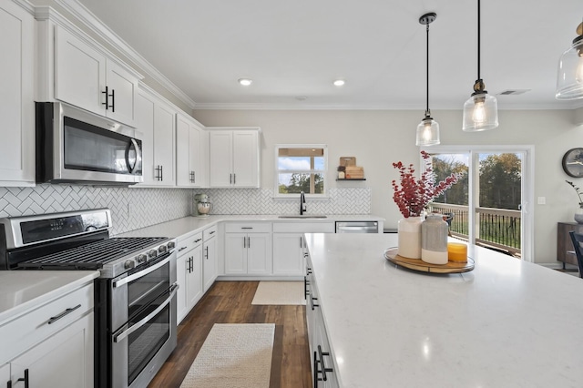 kitchen featuring sink, pendant lighting, stainless steel appliances, and white cabinetry