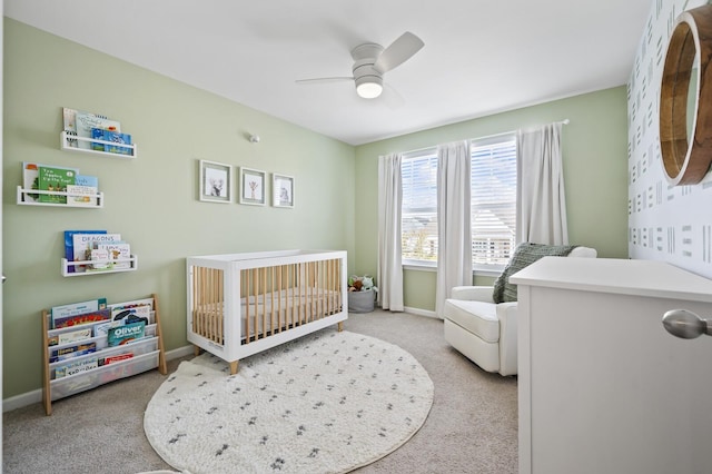 bedroom with ceiling fan, light colored carpet, and a crib