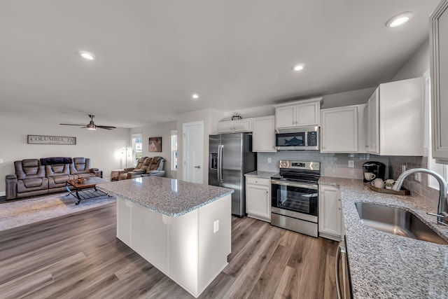 kitchen with tasteful backsplash, appliances with stainless steel finishes, sink, and white cabinetry