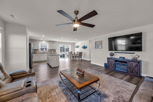 living room featuring ceiling fan and dark wood-type flooring