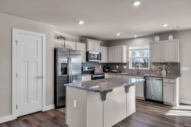 kitchen featuring a kitchen island, sink, appliances with stainless steel finishes, white cabinets, and stone countertops