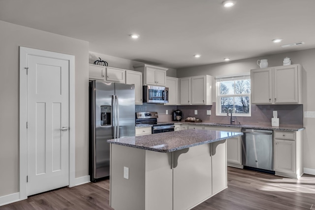 kitchen featuring white cabinets, a kitchen island, stainless steel appliances, sink, and stone counters