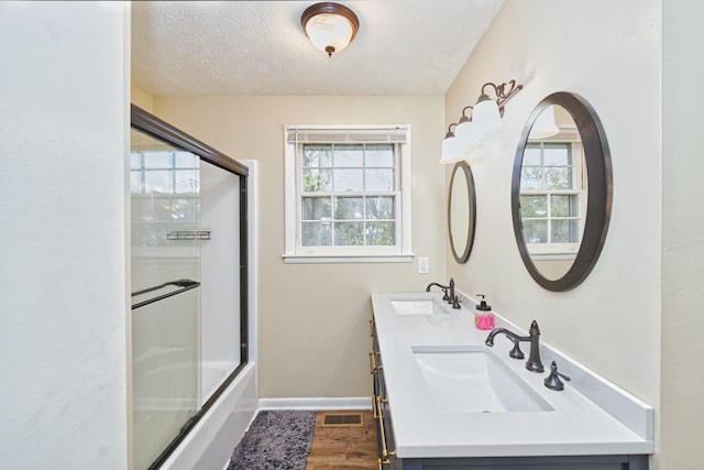 bathroom featuring enclosed tub / shower combo, vanity, and a textured ceiling