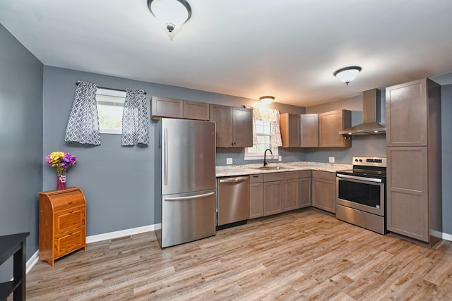 kitchen featuring plenty of natural light, wall chimney range hood, sink, and stainless steel appliances