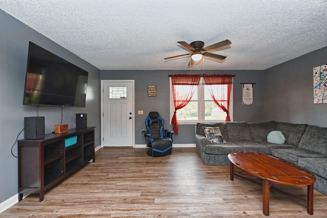 living room with ceiling fan, a textured ceiling, and light hardwood / wood-style flooring