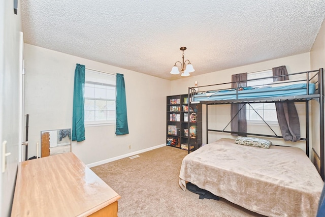 carpeted bedroom featuring a textured ceiling, an inviting chandelier, and multiple windows