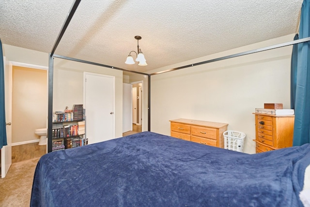 bedroom with a textured ceiling, ensuite bathroom, and a notable chandelier