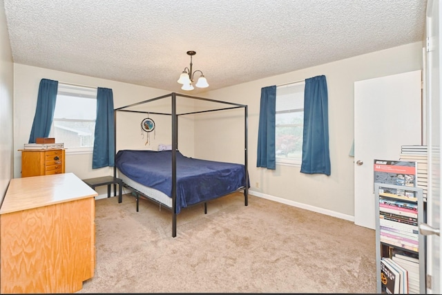 bedroom featuring light carpet, a notable chandelier, a textured ceiling, and multiple windows