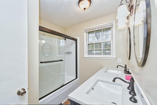 bathroom featuring a textured ceiling, shower / bath combination with glass door, and vanity