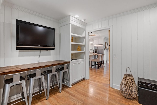 living room with built in features, ornamental molding, and light hardwood / wood-style floors