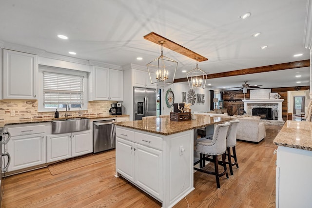 kitchen with hanging light fixtures, appliances with stainless steel finishes, a kitchen island, and sink