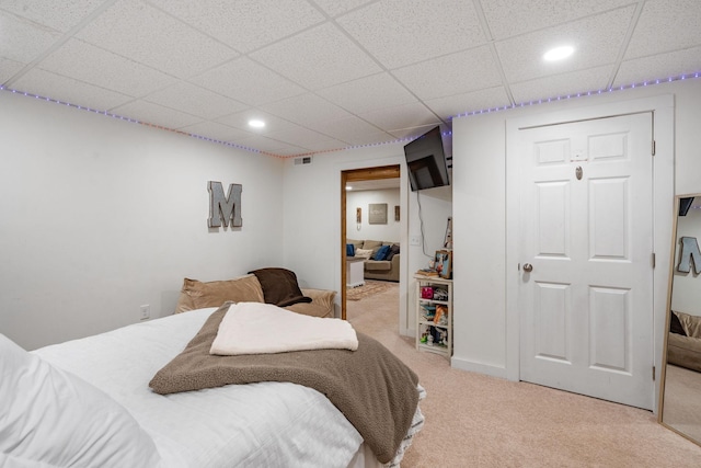 carpeted bedroom with a closet and a paneled ceiling