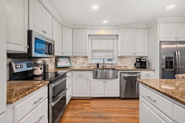 kitchen with sink, dark stone countertops, stainless steel appliances, and white cabinetry