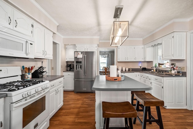 kitchen featuring a kitchen island, a wealth of natural light, sink, white appliances, and white cabinets