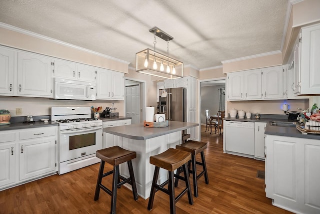 kitchen featuring white cabinetry, white appliances, a textured ceiling, a breakfast bar, and sink