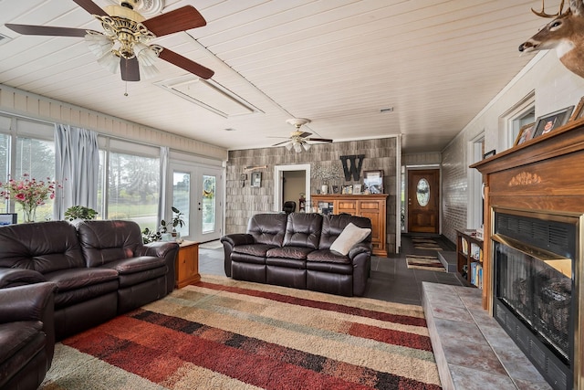 living room featuring dark tile patterned floors, a tile fireplace, and wooden walls