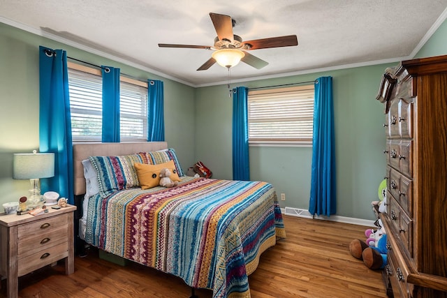 bedroom featuring ceiling fan, hardwood / wood-style floors, ornamental molding, and a textured ceiling