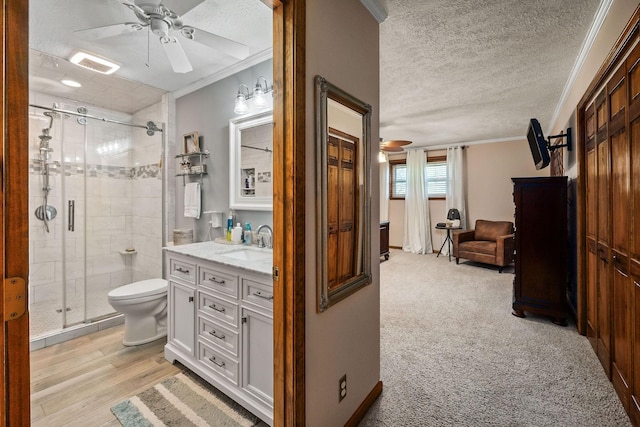 bathroom featuring walk in shower, vanity, ceiling fan, and crown molding