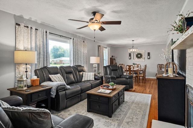 living room featuring a textured ceiling, ceiling fan with notable chandelier, crown molding, and light hardwood / wood-style floors