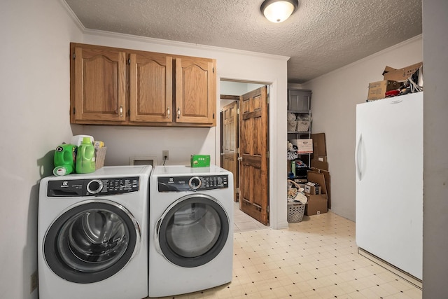 laundry area featuring a textured ceiling, cabinets, ornamental molding, and washer and clothes dryer