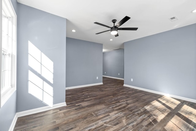 empty room with ceiling fan, a wealth of natural light, and dark hardwood / wood-style floors