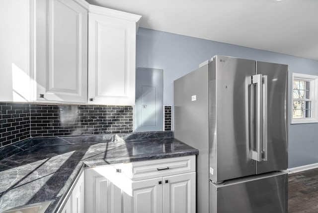 kitchen with backsplash, dark stone countertops, high quality fridge, white cabinetry, and dark wood-type flooring