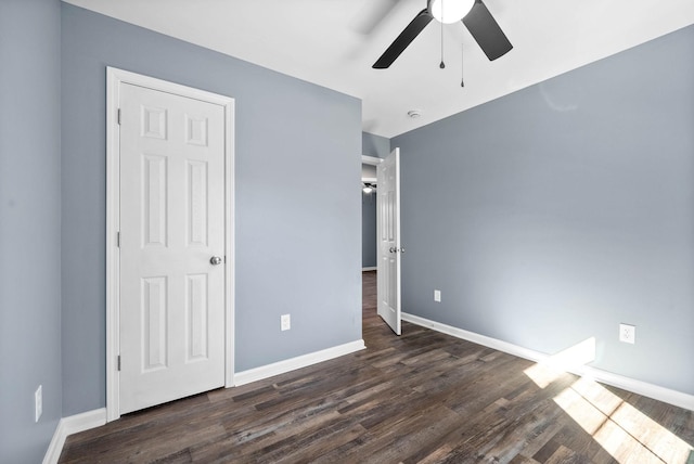 unfurnished bedroom with ceiling fan and dark wood-type flooring