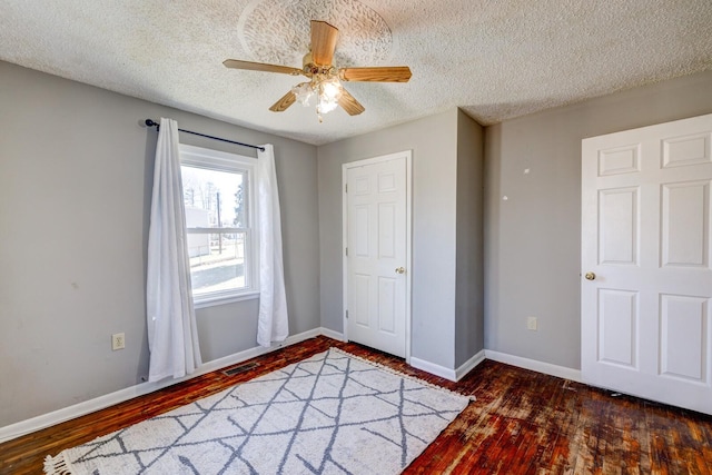 unfurnished bedroom featuring a textured ceiling, ceiling fan, and dark hardwood / wood-style floors