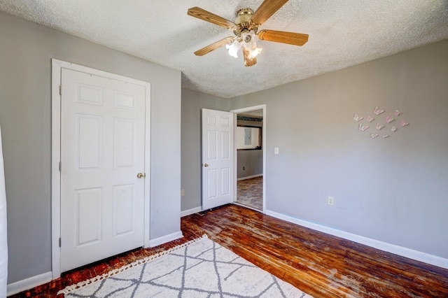 unfurnished bedroom with ceiling fan, dark hardwood / wood-style floors, and a textured ceiling