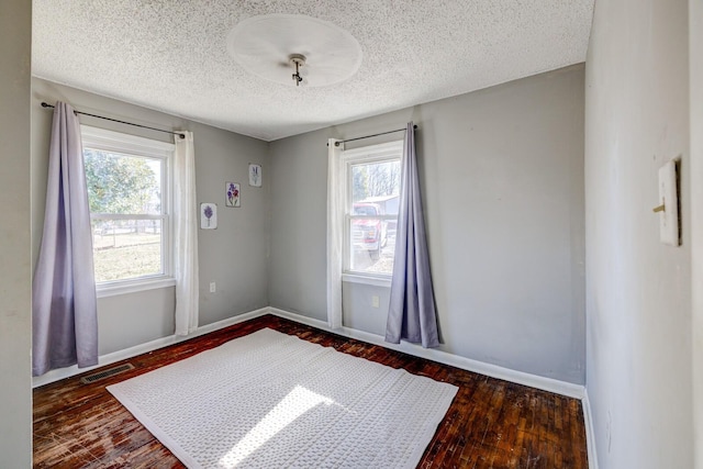 unfurnished room featuring dark wood-type flooring and a textured ceiling