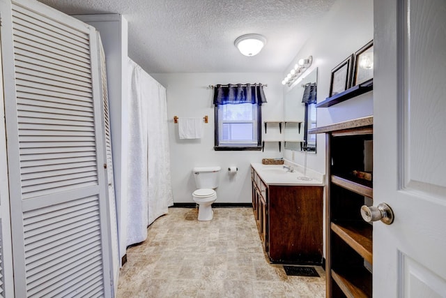 bathroom with a textured ceiling, toilet, and vanity