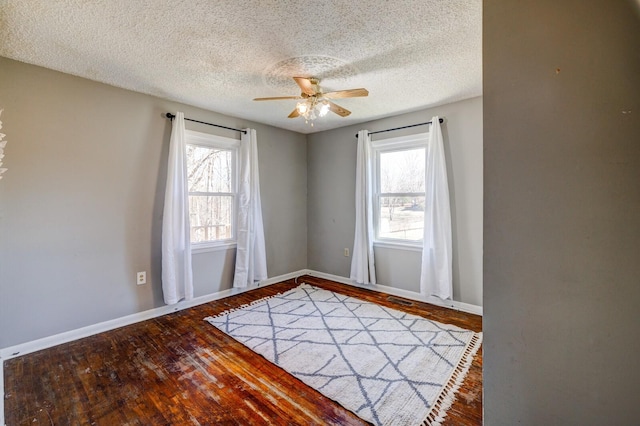 spare room featuring a textured ceiling, a healthy amount of sunlight, and hardwood / wood-style flooring