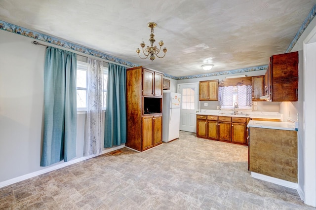 kitchen with sink, hanging light fixtures, a chandelier, and white fridge