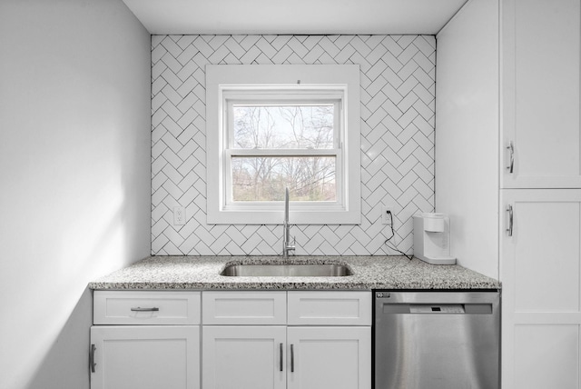 kitchen featuring backsplash, dishwasher, sink, white cabinets, and light stone counters