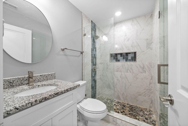 bathroom featuring toilet, vanity, and tiled shower