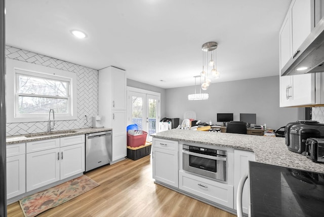 kitchen featuring pendant lighting, white cabinets, appliances with stainless steel finishes, tasteful backsplash, and sink