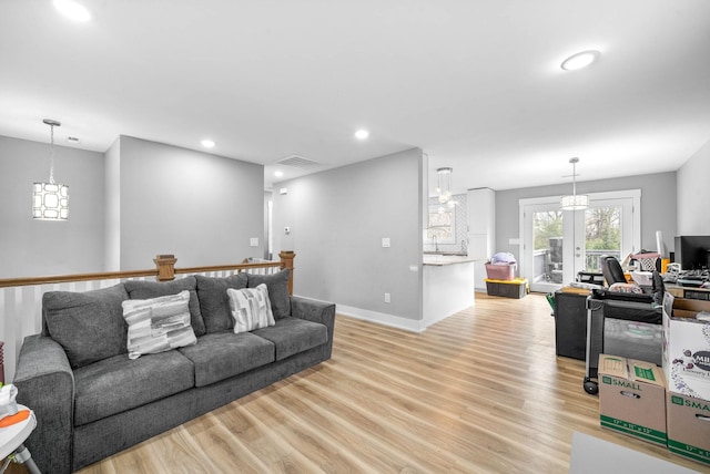 living room with french doors, sink, and light hardwood / wood-style flooring