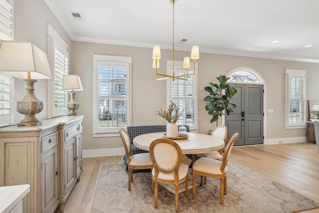 dining space with light wood-type flooring, an inviting chandelier, and ornamental molding