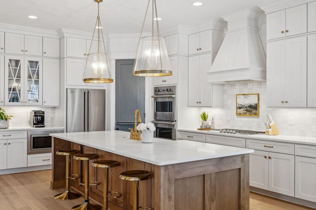 kitchen with white cabinetry, appliances with stainless steel finishes, and custom range hood