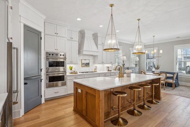 kitchen featuring decorative light fixtures, white cabinets, sink, and custom range hood